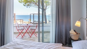 Ein Hotelzimmer mit Bett, Tisch mit Stühlen, Meerblick und einem Balkon mit Tisch und Stühlen.