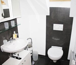 A modern bathroom with a white sink, mirror, and toilet.