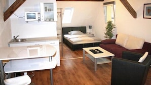 A compact living space with a kitchenette, a bed, a sofa, and a small table. - Hermann's Neue Post (Calw)