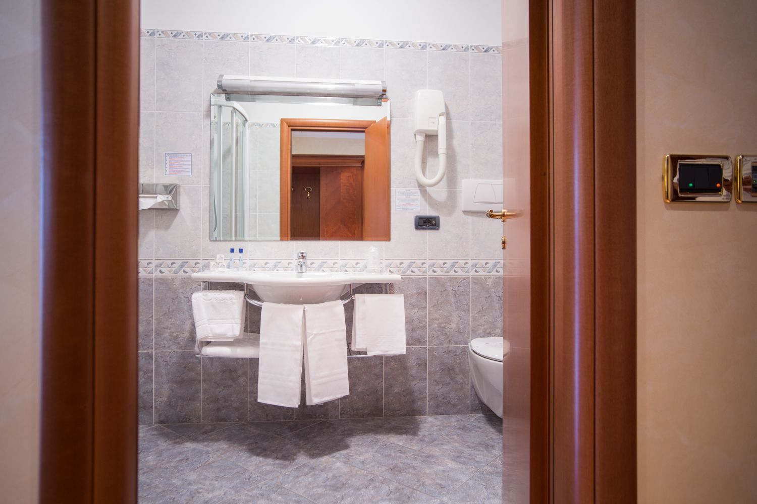 Ein Badezimmer mit Waschbecken, Spiegel, Handtuchhalter und Toilette.