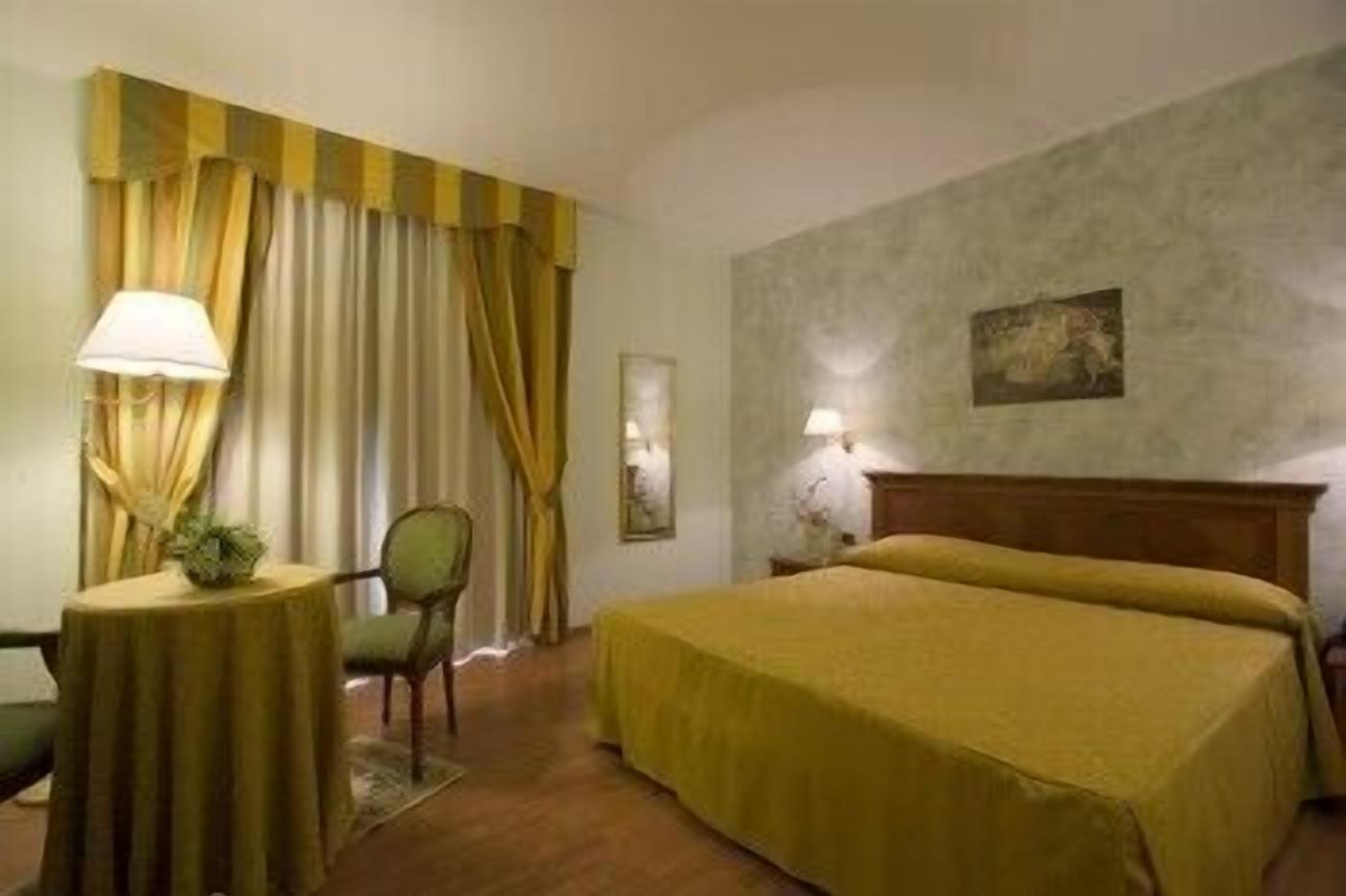 Una camera d'albergo con un letto, una sedia, un tavolino e tende.