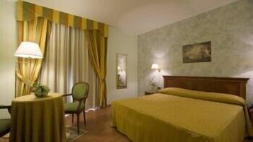 Una camera d'albergo con un letto, una sedia, un tavolino e tende.