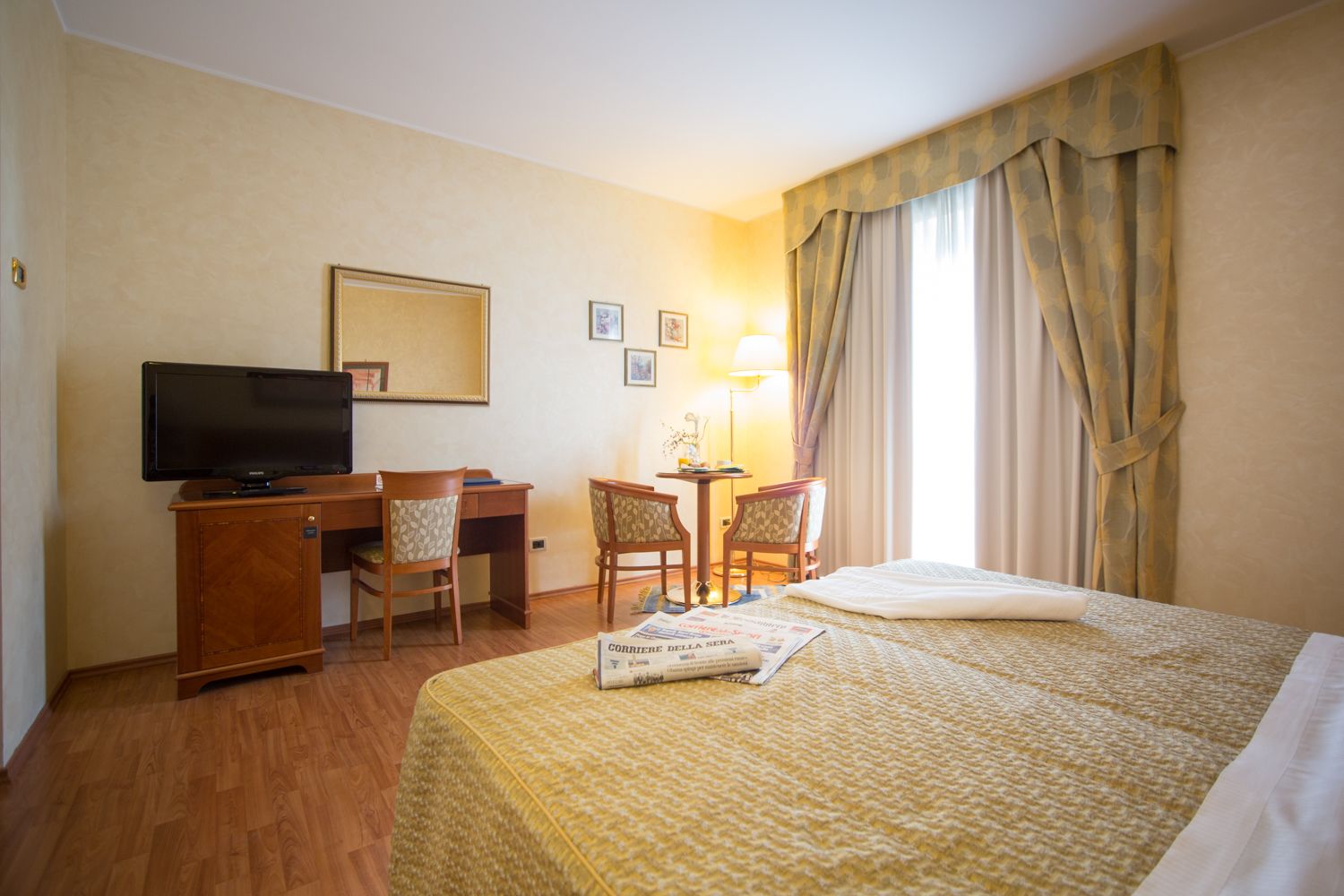 Een hotelkamer met een bed, een bureau, een televisie en een stoel.