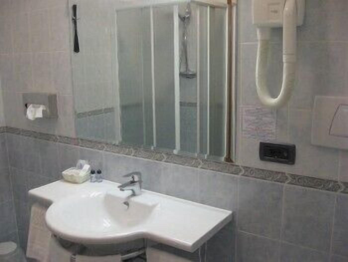 Un baño con lavamanos blanco, espejo y ducha.