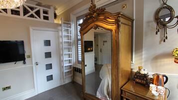 A bedroom with a large mirror, a wardrobe, a television, and a ladder.