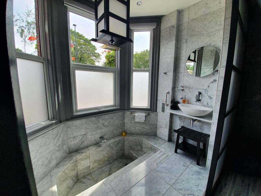 A modern bathroom with a large bathtub, a sink, and a mirror.