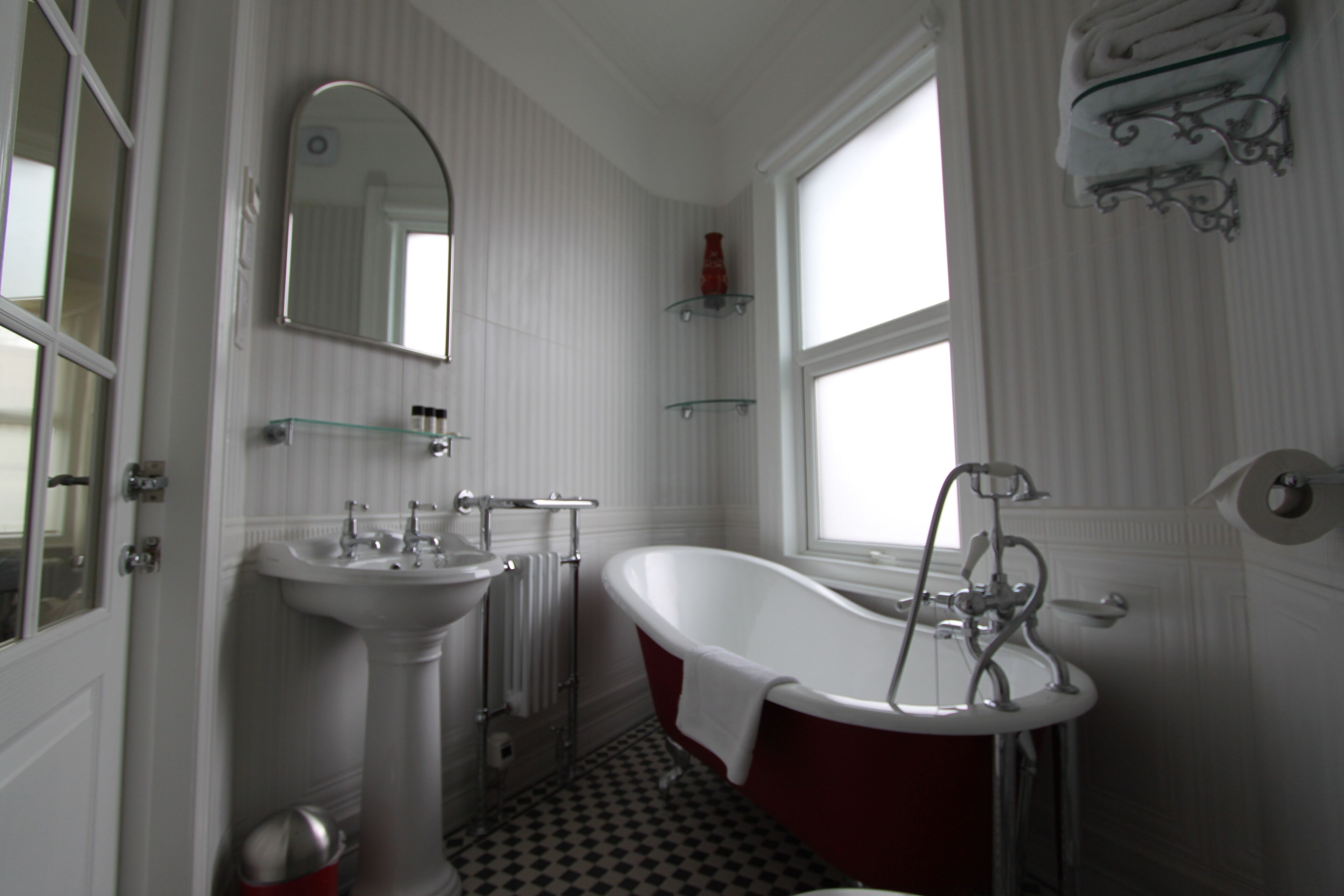 A bathroom with a white sink, a freestanding bathtub, a mirror, and a window.