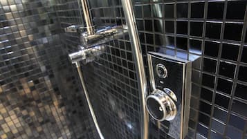 A shower enclosure with a chrome shower head and control panel, set against a tiled wall.