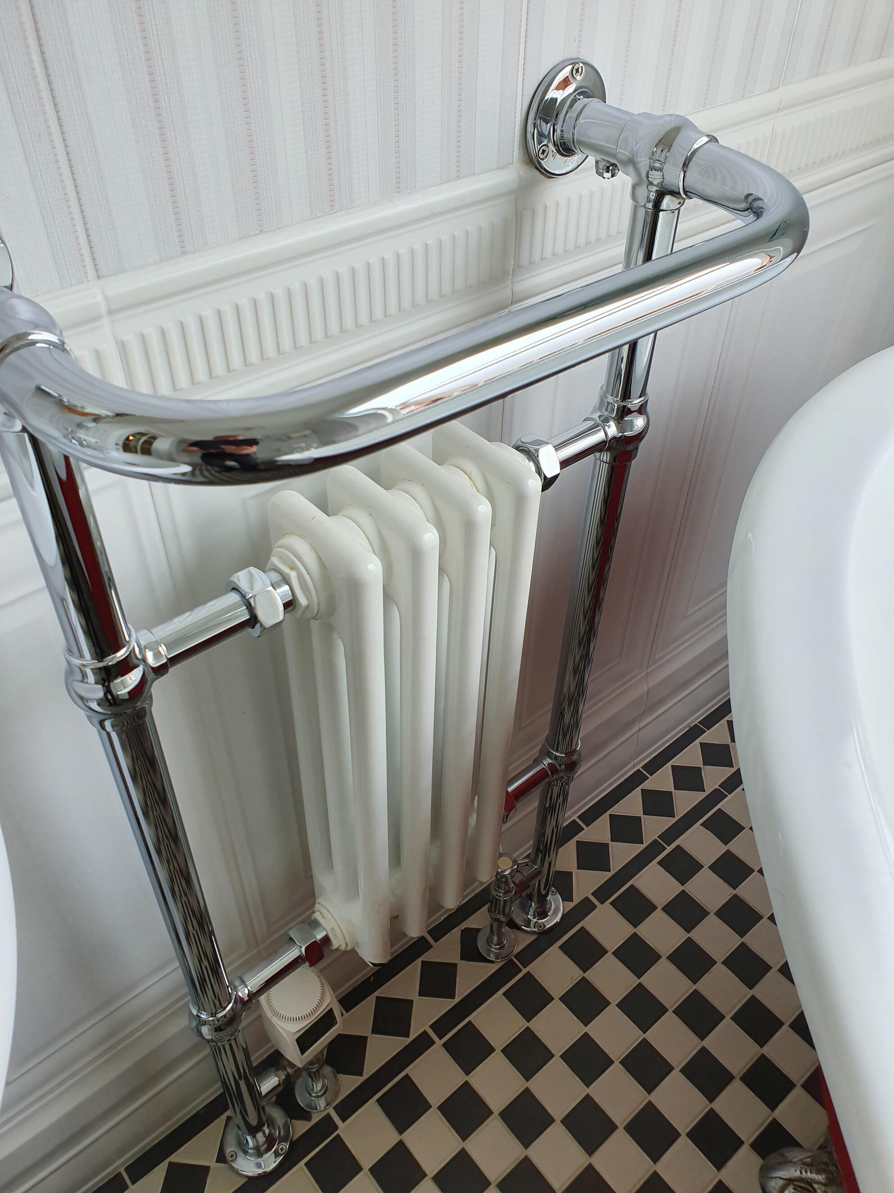 A bathroom with a chrome bathtub, a white radiator, and a checkered floor.