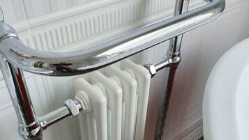 A bathroom with a chrome bathtub, a white radiator, and a checkered floor.