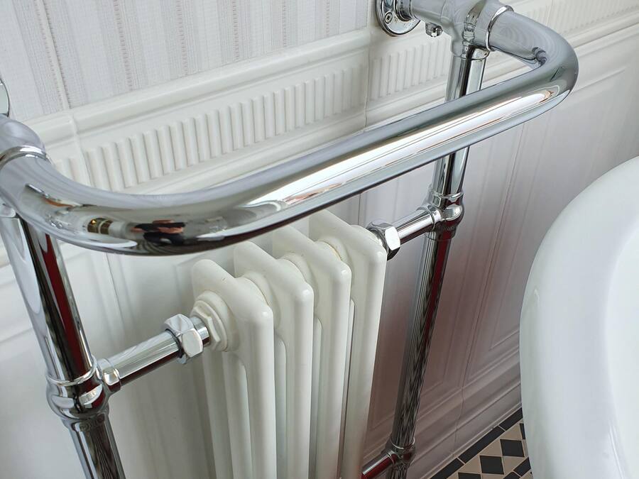 A bathroom with a chrome bathtub, a white radiator, and a checkered floor.