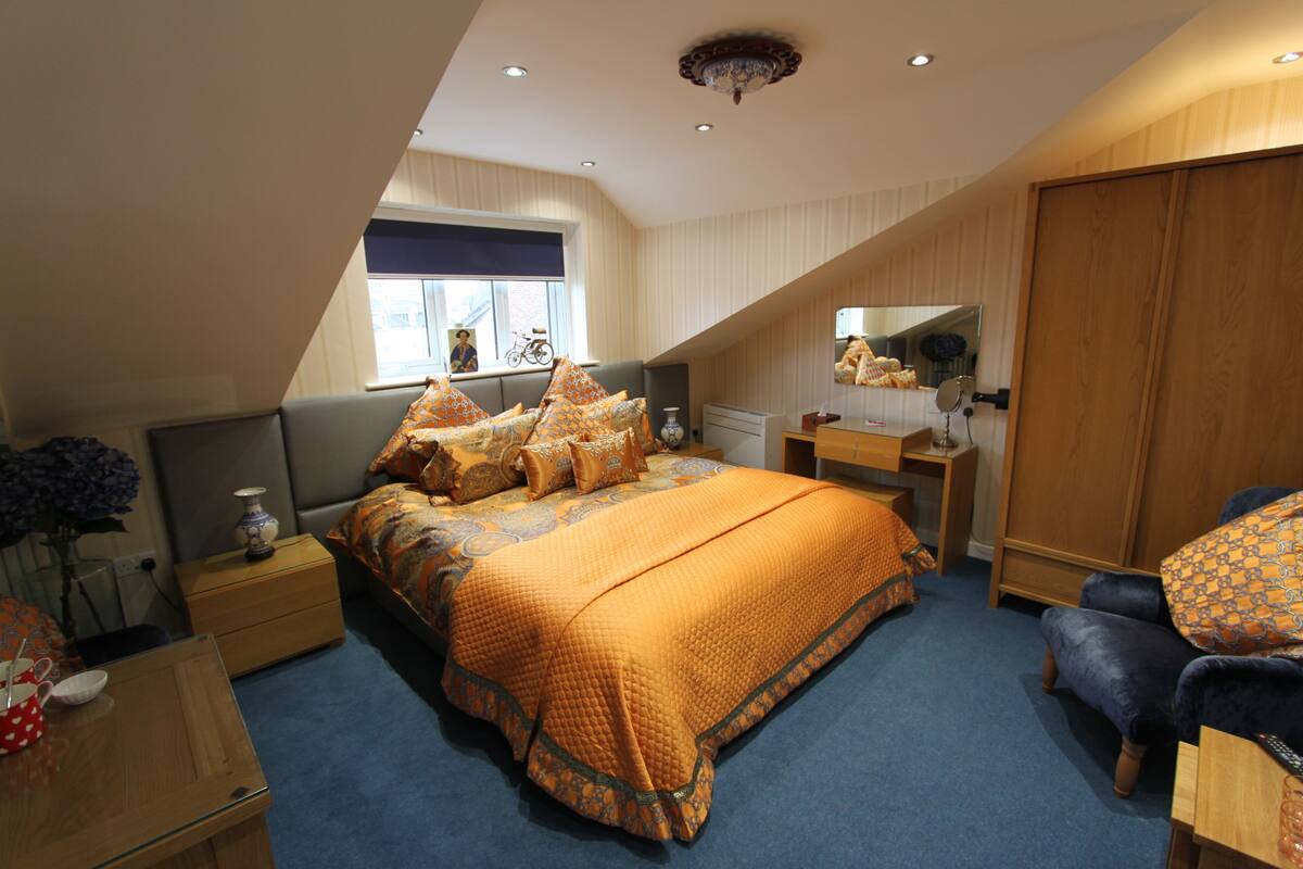 A bedroom with a bed, a nightstand, a dresser, a chair, a window, and a mirror.