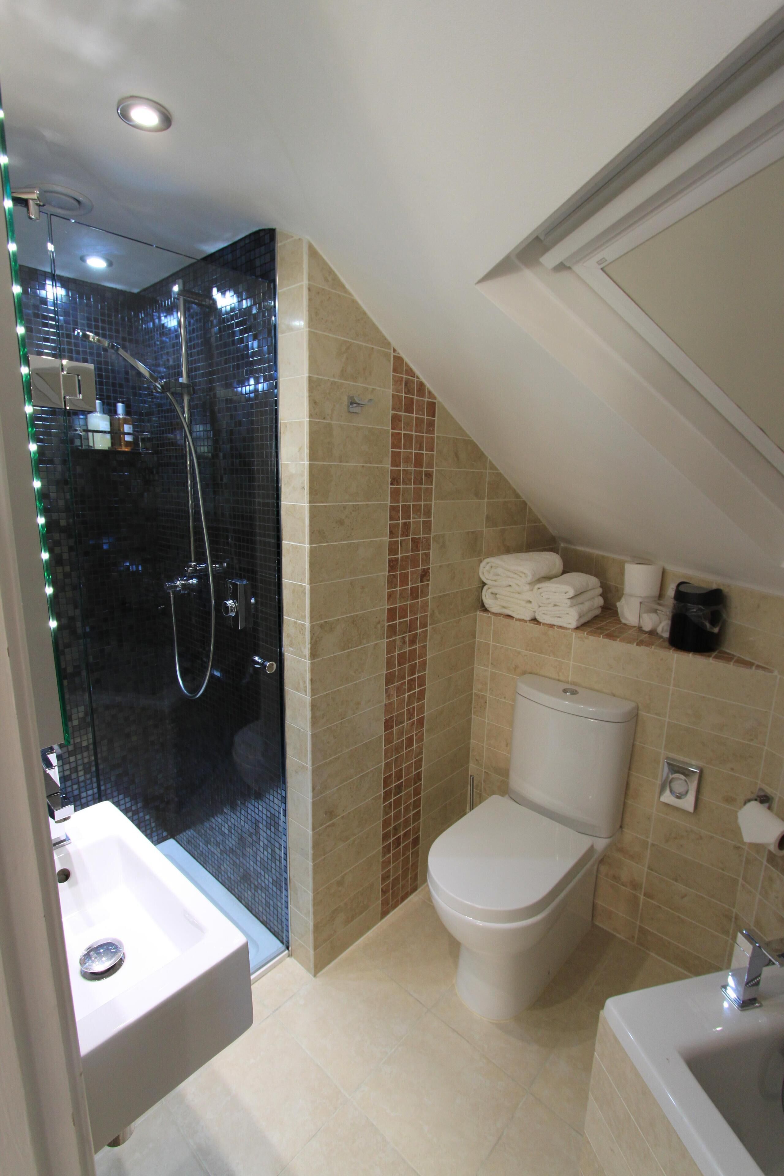 Un baño con cabina de ducha de vidrio, inodoro y lavamanos.