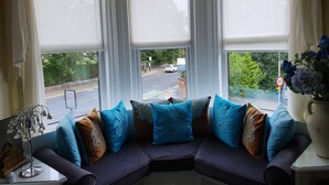 A corner seating area with a sofa, decorative pillows, and a vase of flowers. - Tower Guest House (York)
