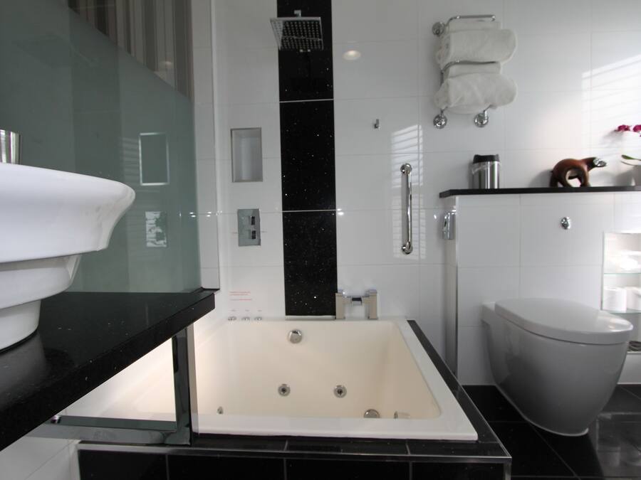A modern bathroom with a bathtub, toilet, and glass shower enclosure.