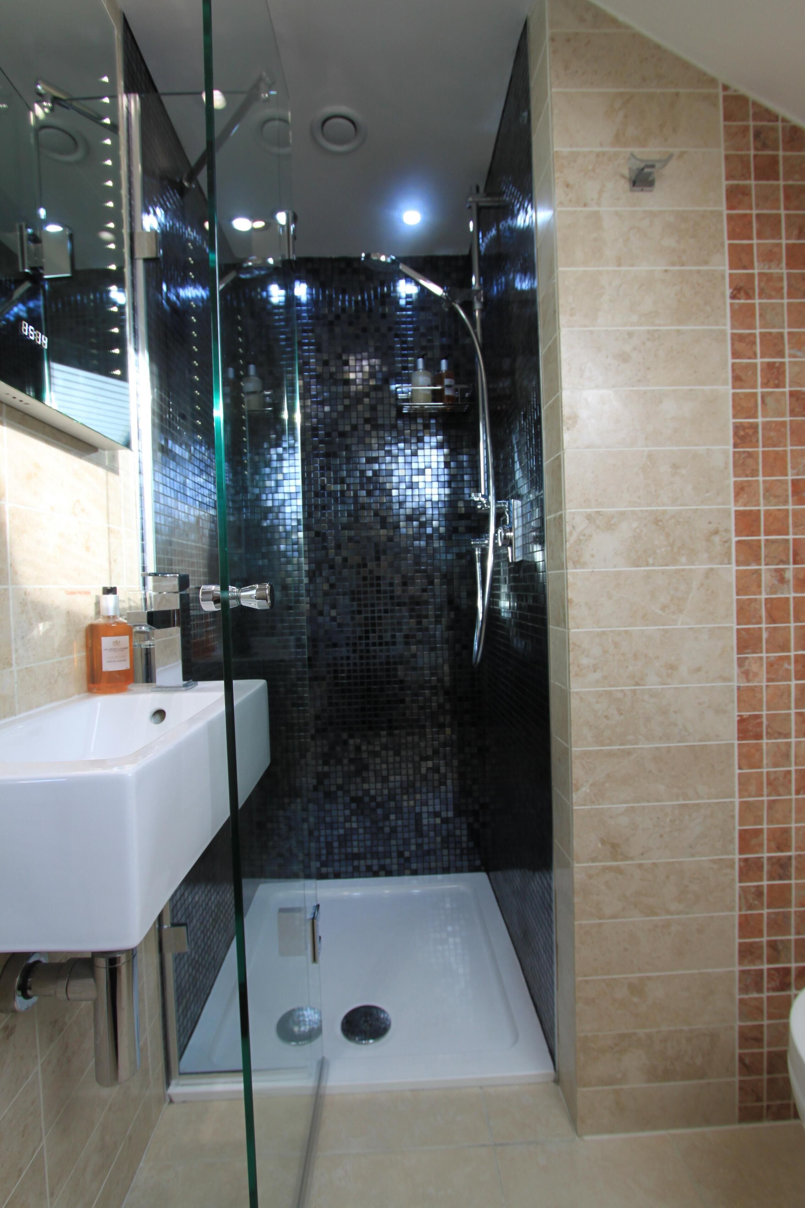 A modern bathroom with a glass-enclosed shower, a white sink, and a tiled backsplash.
