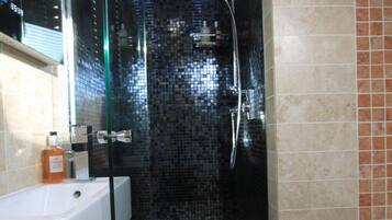 A modern bathroom with a glass-enclosed shower, a white sink, and a tiled backsplash.