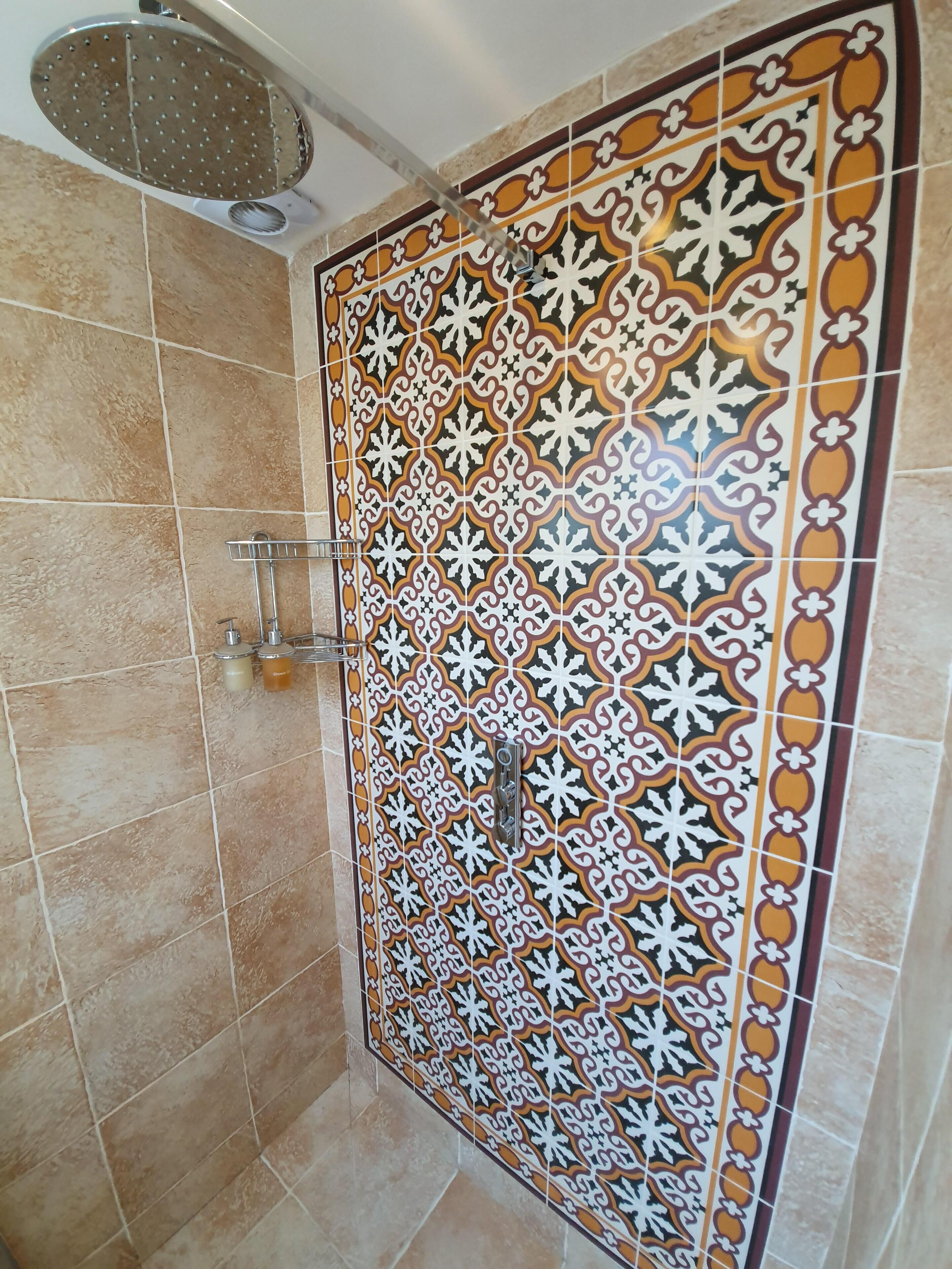 A bathroom with patterned tiles, a showerhead, and a towel rack.