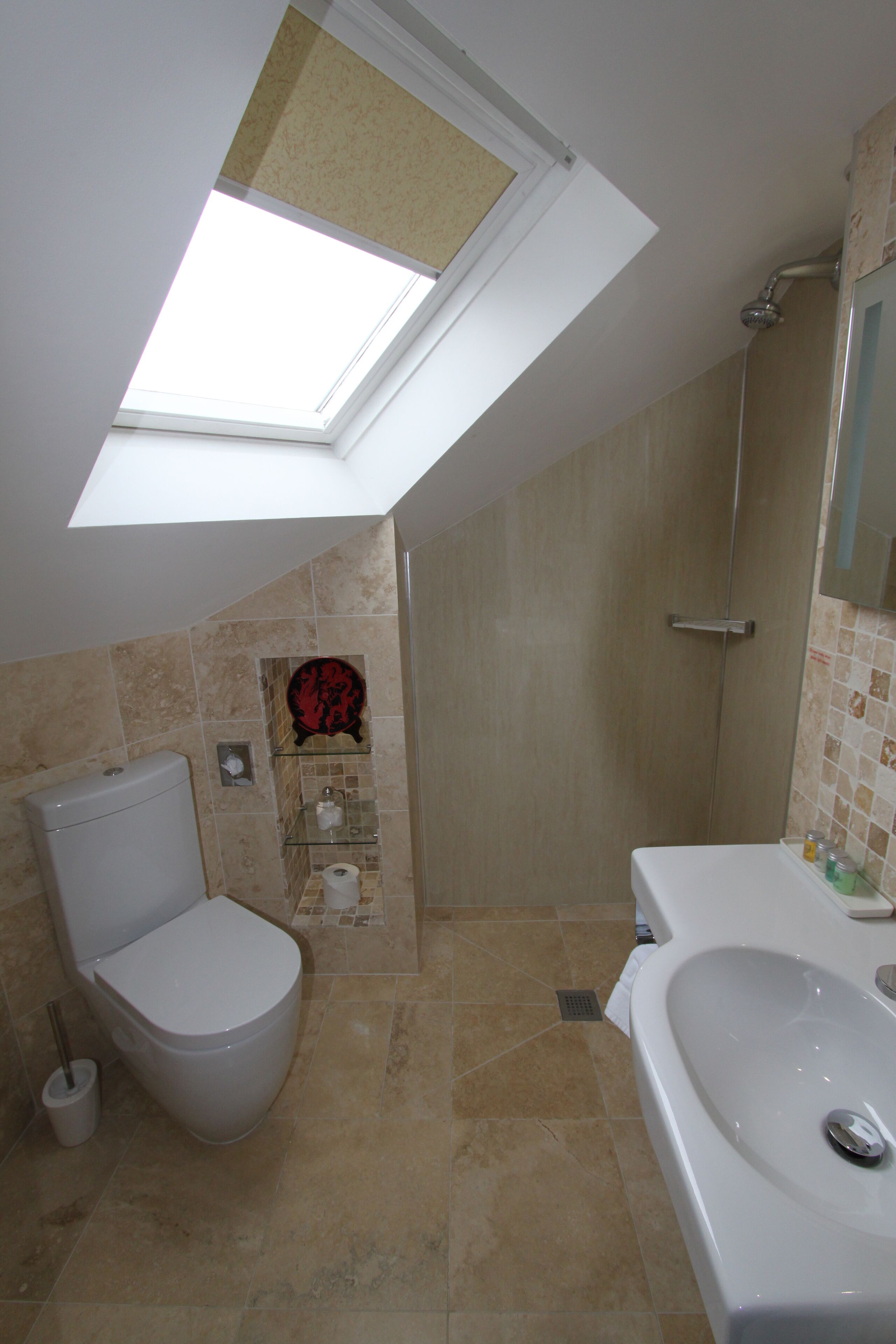 Une salle de bain avec un puits de lumière, des toilettes, une douche et une baignoire.