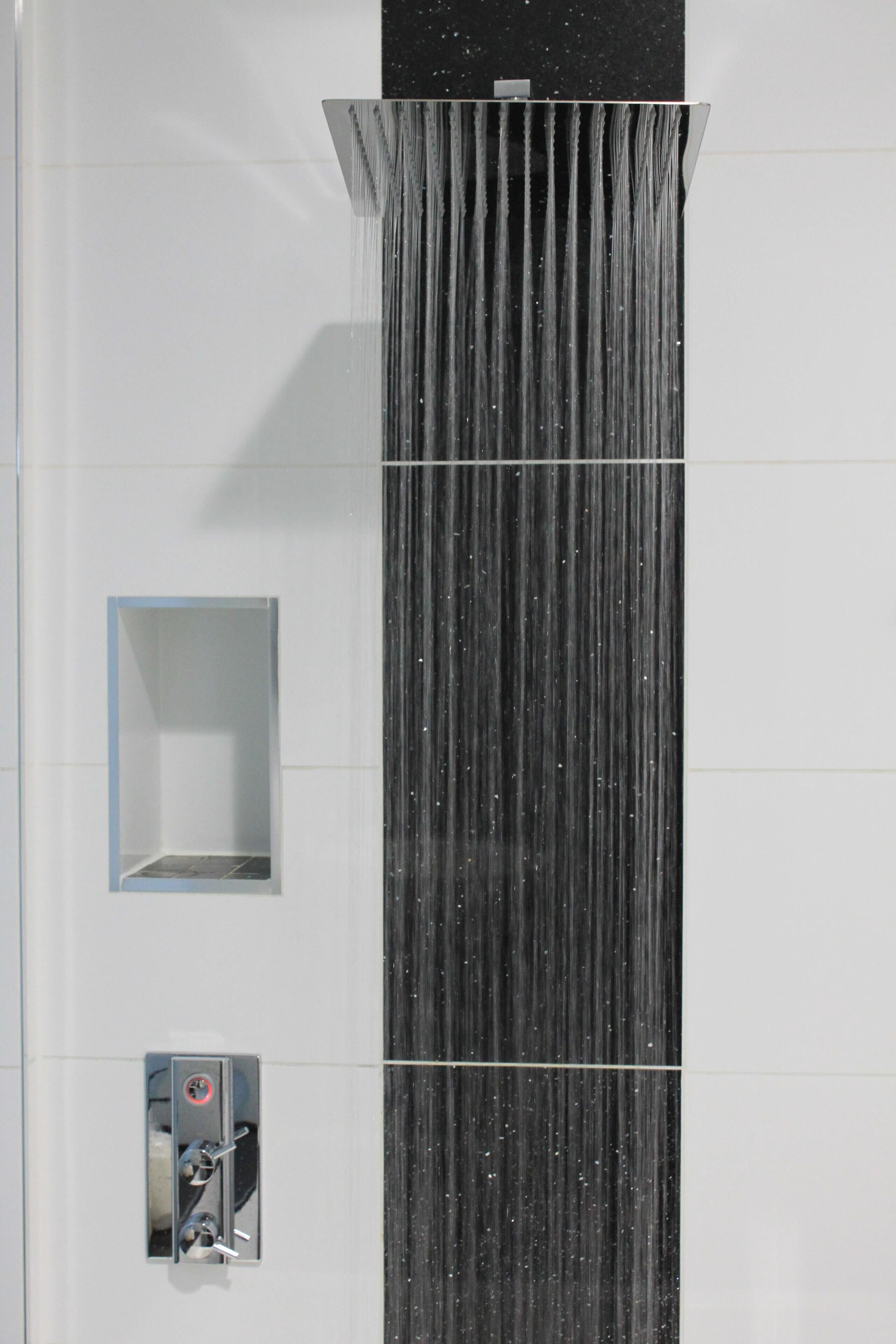 Chuveiro moderno com um recurso vertical de água e um painel de controle.