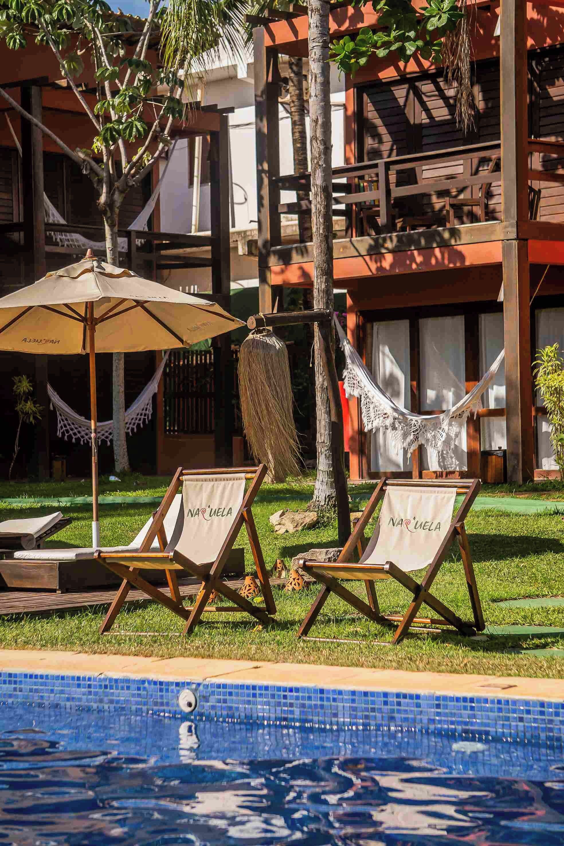 Un área junto a la piscina con dos sillas reclinables, una hamaca y piscina.