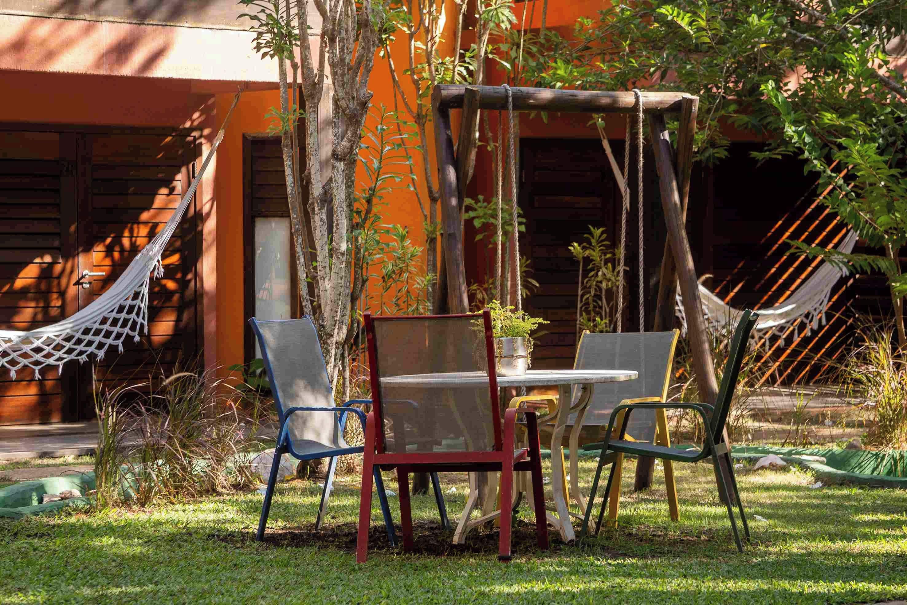 Una hamaca, una mesa y sillas en un jardín, con un edificio al fondo.