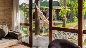 Una habitación con un ventanal grande, una hamaca y vistas a un jardín con una estructura de madera.