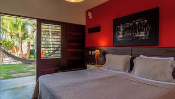 Habitación de hotel con cama, mesita de noche, lámpara, un cuadro y vista al exterior.