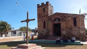 A church with a stone tower and a cross in front. - Pousada Naquela (Jijoca de Jericoacoara)