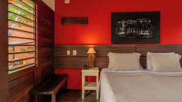 Una habitación de hotel con cama, mesita de noche, lámpara y un cuadro colgado en la pared.