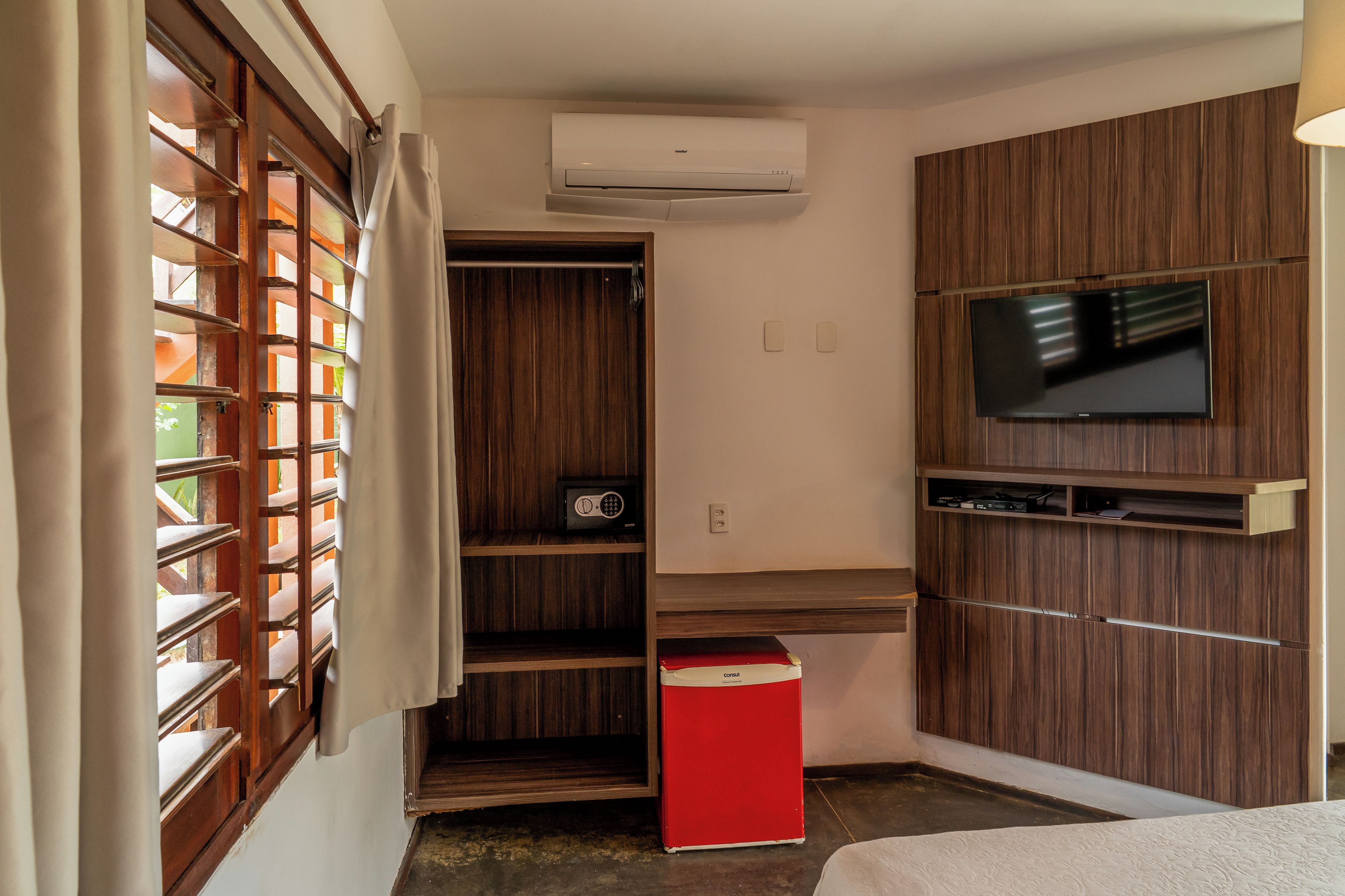 A compact room with a wardrobe, a television, and a small red cabinet.