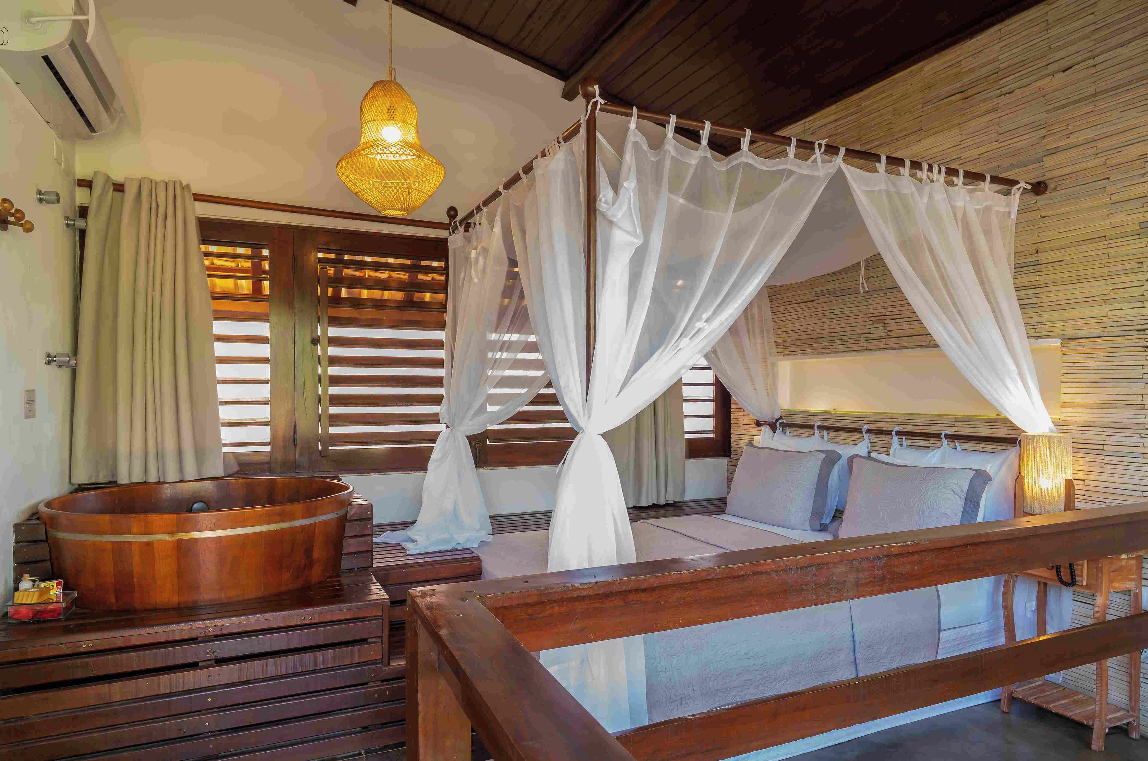 Una habitación con una cama de madera, una bañera de madera y un dosel.