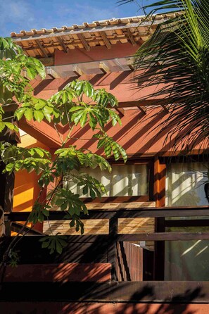 A building with a tiled roof, large windows, and a tree with broad leaves in front. - Pousada Naquela (Jijoca de Jericoacoara)