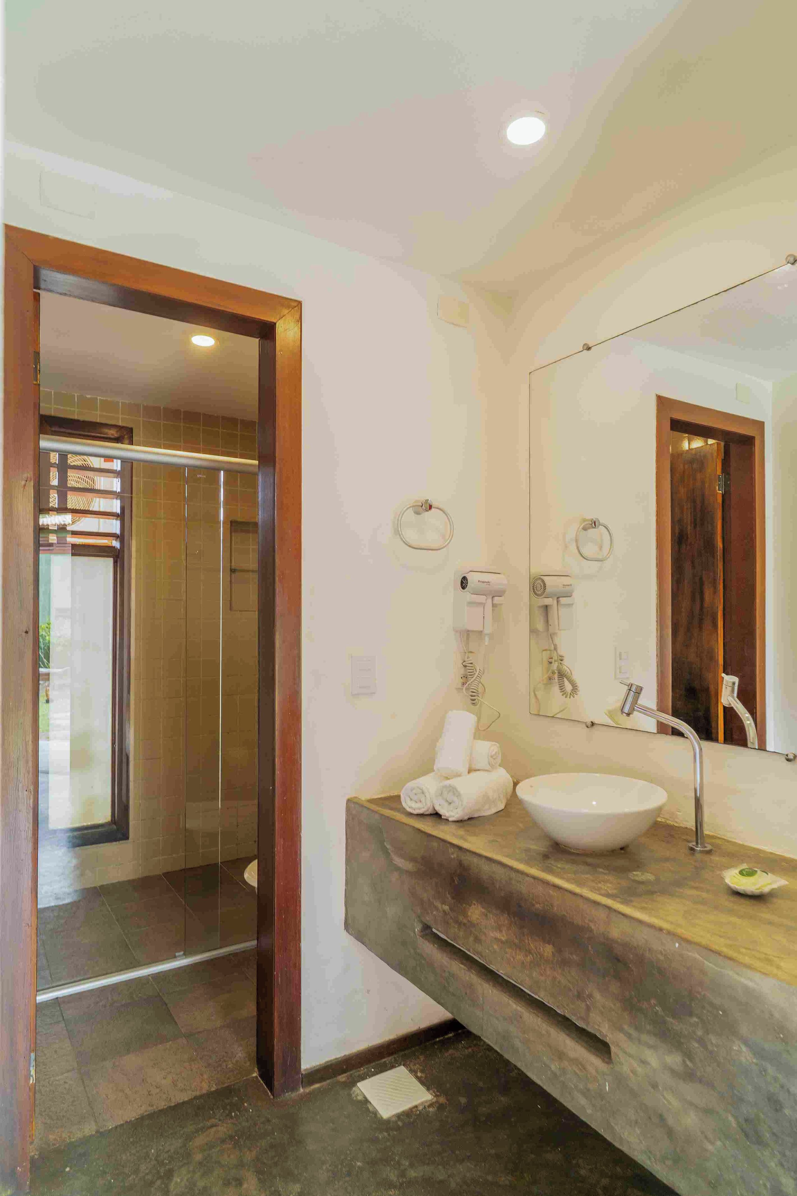 Un baño con tocador de madera, un espejo grande, un lavamanos y un perchero para toallas.