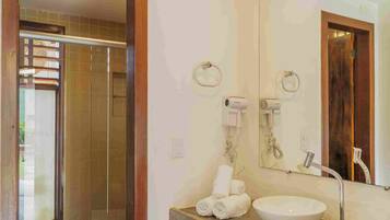 Un baño con tocador de madera, un espejo grande, un lavamanos y un perchero para toallas.