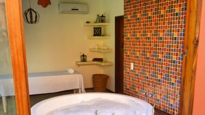 A bathroom with a bathtub, a mirror, and a tiled wall. - Pousada Naquela (Jijoca de Jericoacoara)