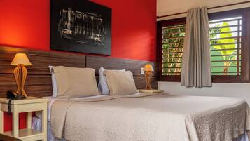 A hotel room with a large bed, two bedside lamps, a telephone, a painting on the wall, and a window with curtains.