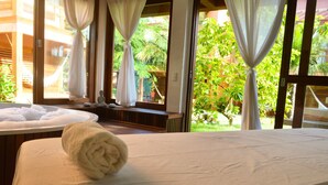 A hotel room with a bed, a window with curtains, and a view of greenery outside. - Pousada Naquela (Jijoca de Jericoacoara)