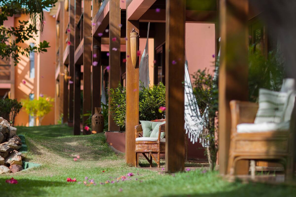 Un coin de jardin aménagé avec un fauteuil en osier, un hamac et un tas de pierres.