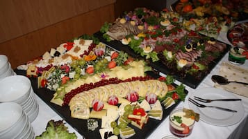 Un bufé con diversos quesos, frutas y embutidos.