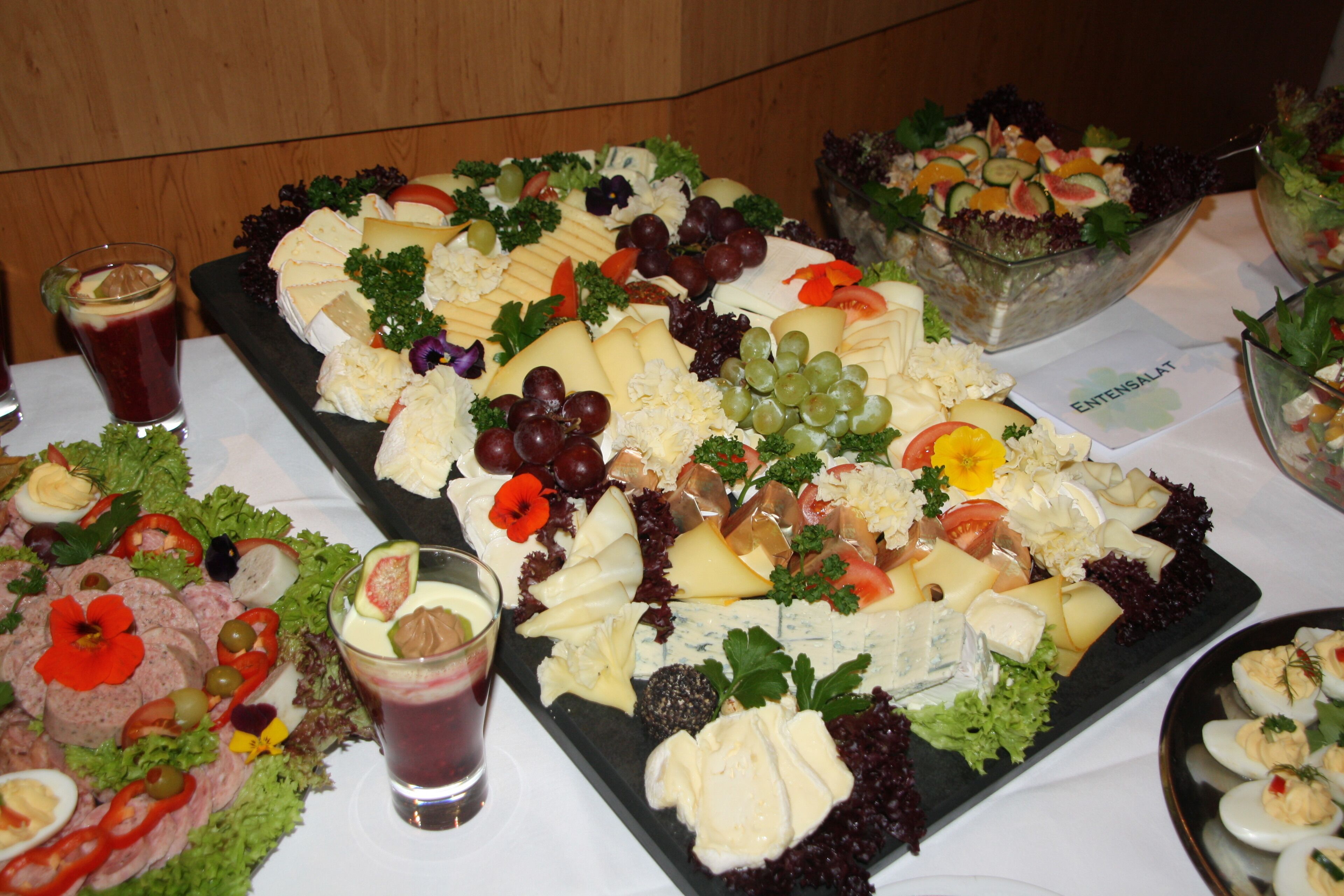Variedad de alimentos, incluyendo queso, uvas y ensaladas, dispuestas sobre una mesa.