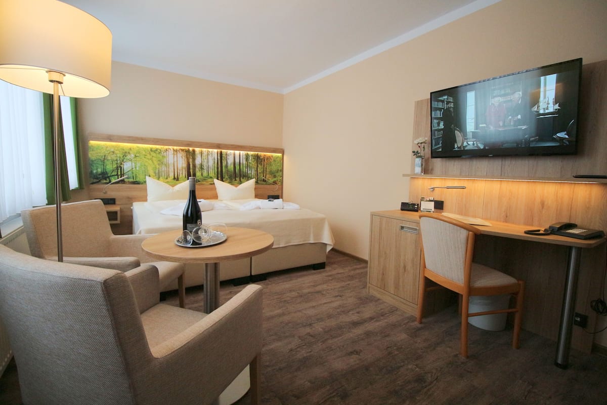 Una habitación de hotel con una cama, un escritorio, una silla, un televisor y una lámpara.