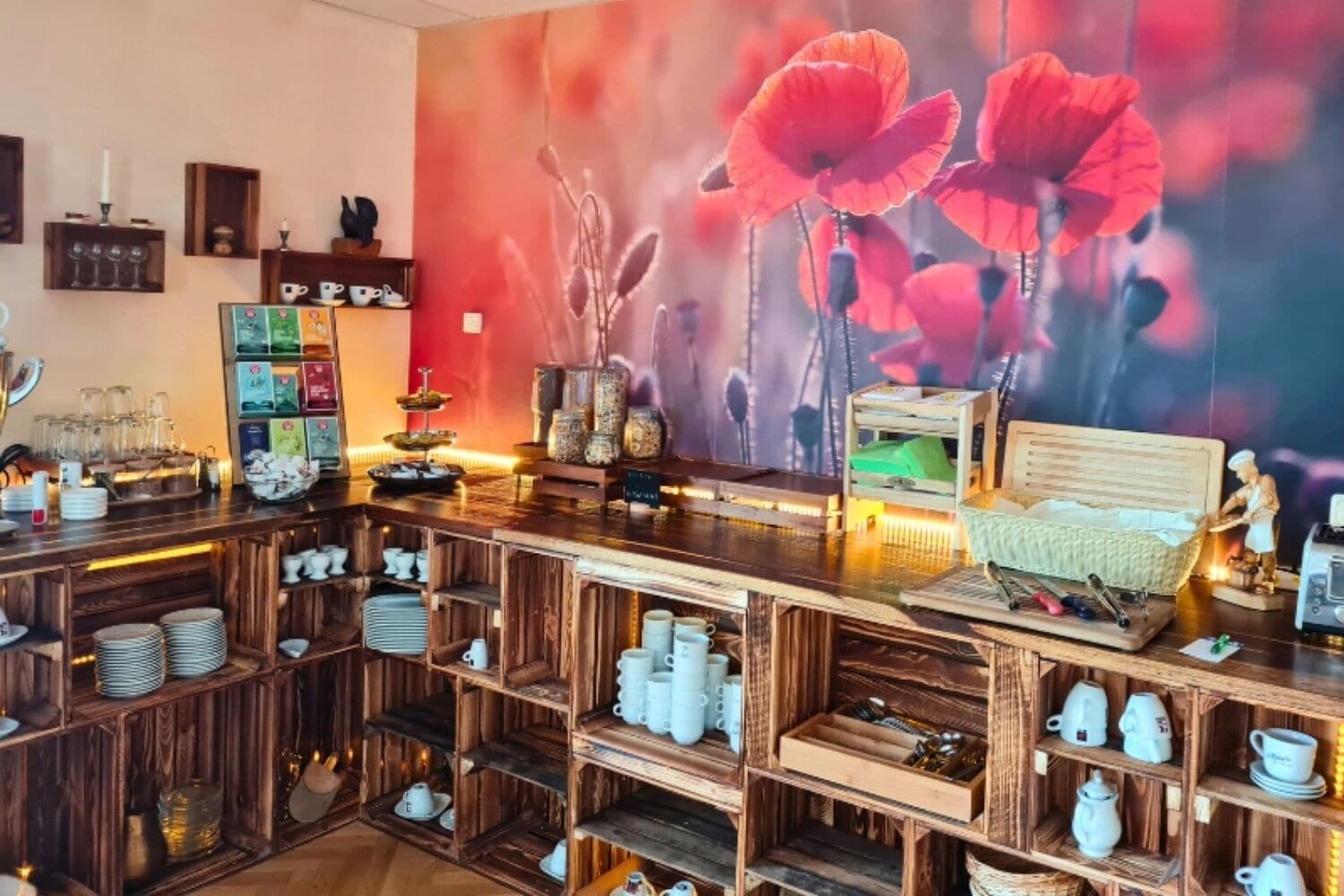 Una zona de bar con estantes de madera, una silla de mimbre y un gran mural con una amapola.