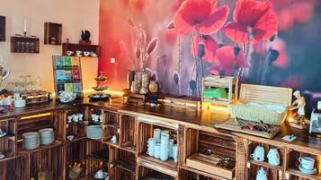 Una zona de bar con estantes de madera, una silla de mimbre y un gran mural con una amapola.