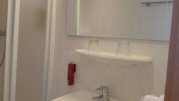 Un baño con lavamanos blanco, un espejo y un cabezal de ducha de mano.