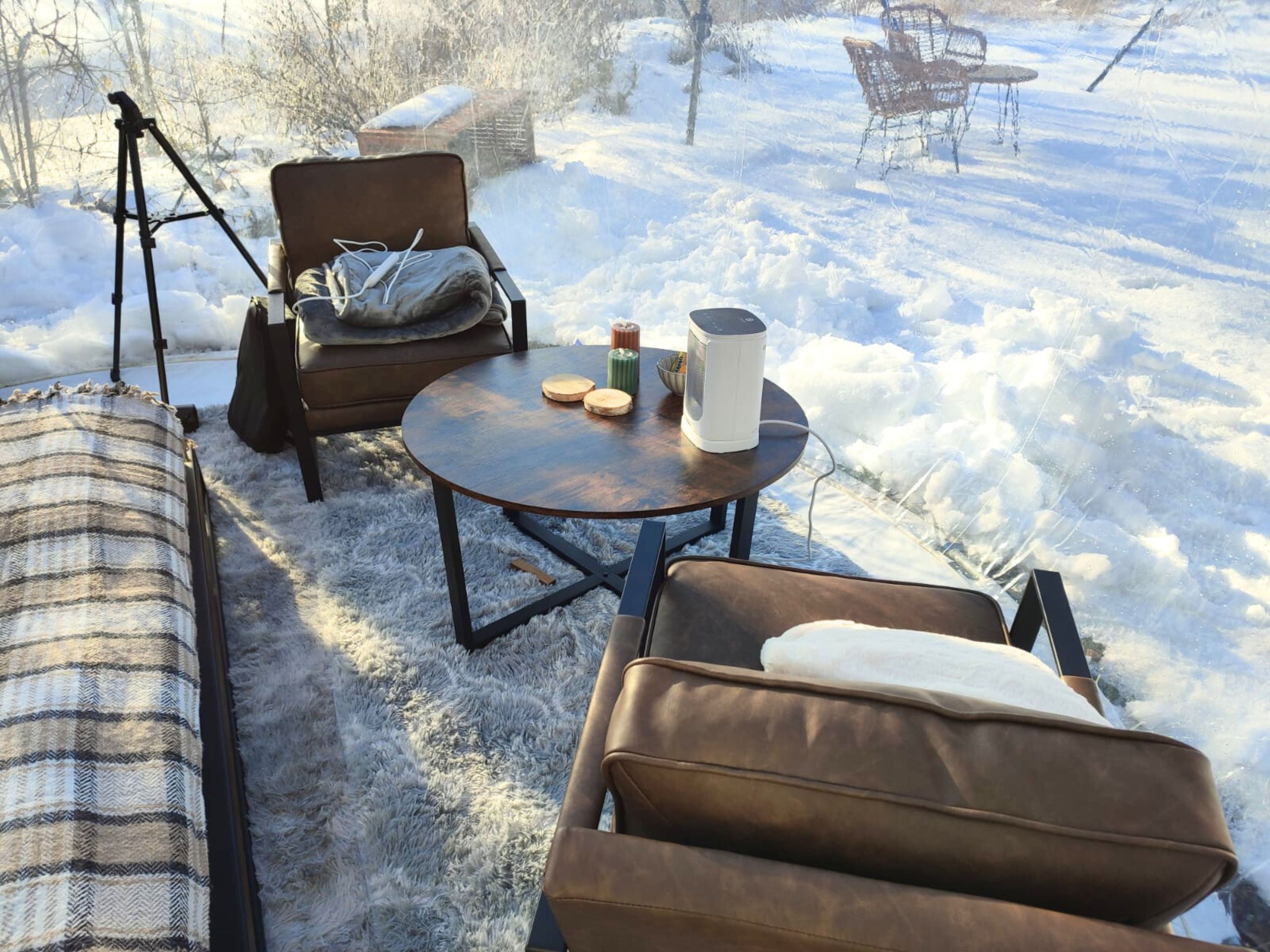 Un espacio al aire libre acogedor con sofá, sillas y una mesa, rodeado de nieve.