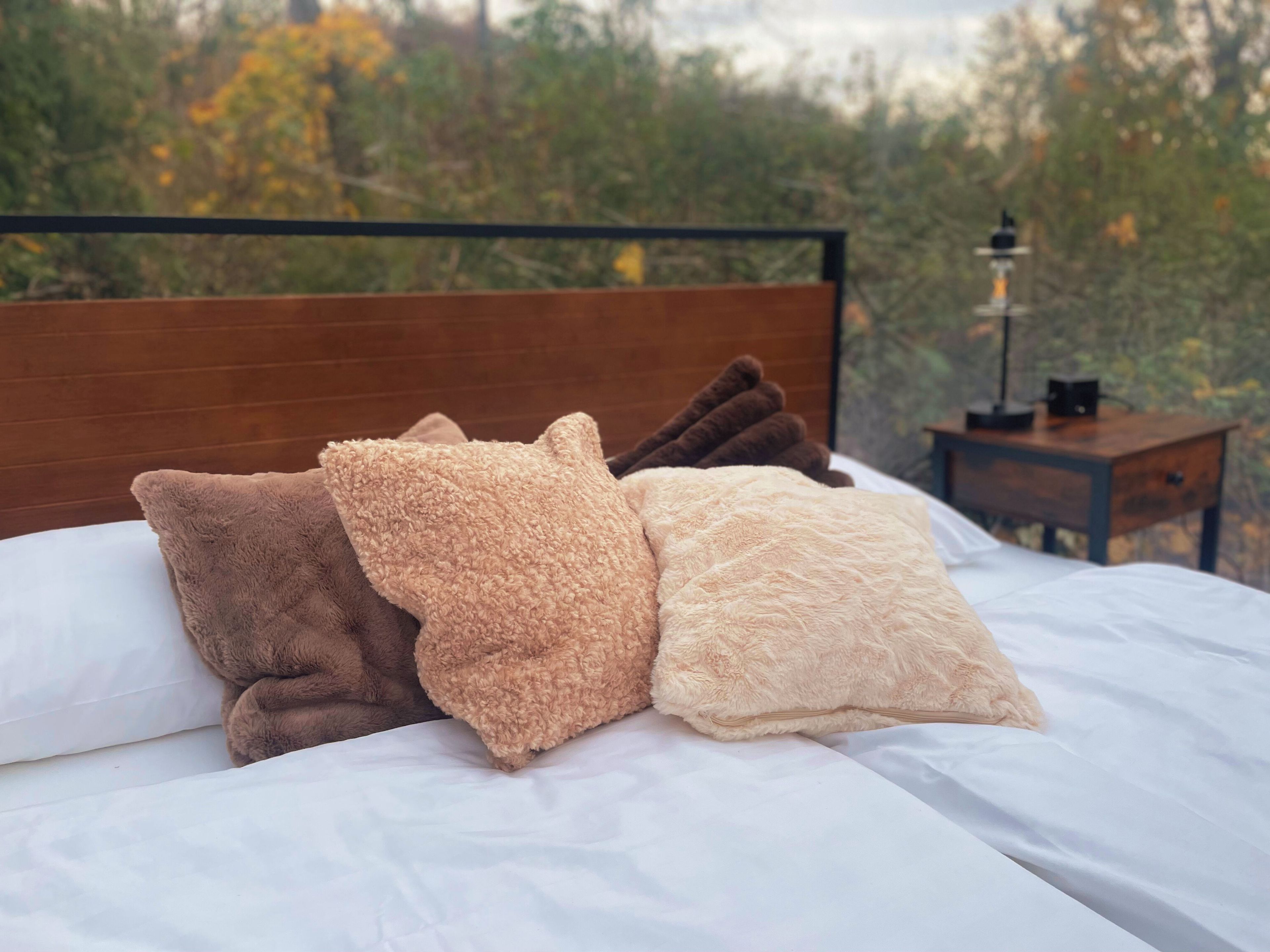 A bed with a wooden headboard, white bedding, and three fluffy pillows.