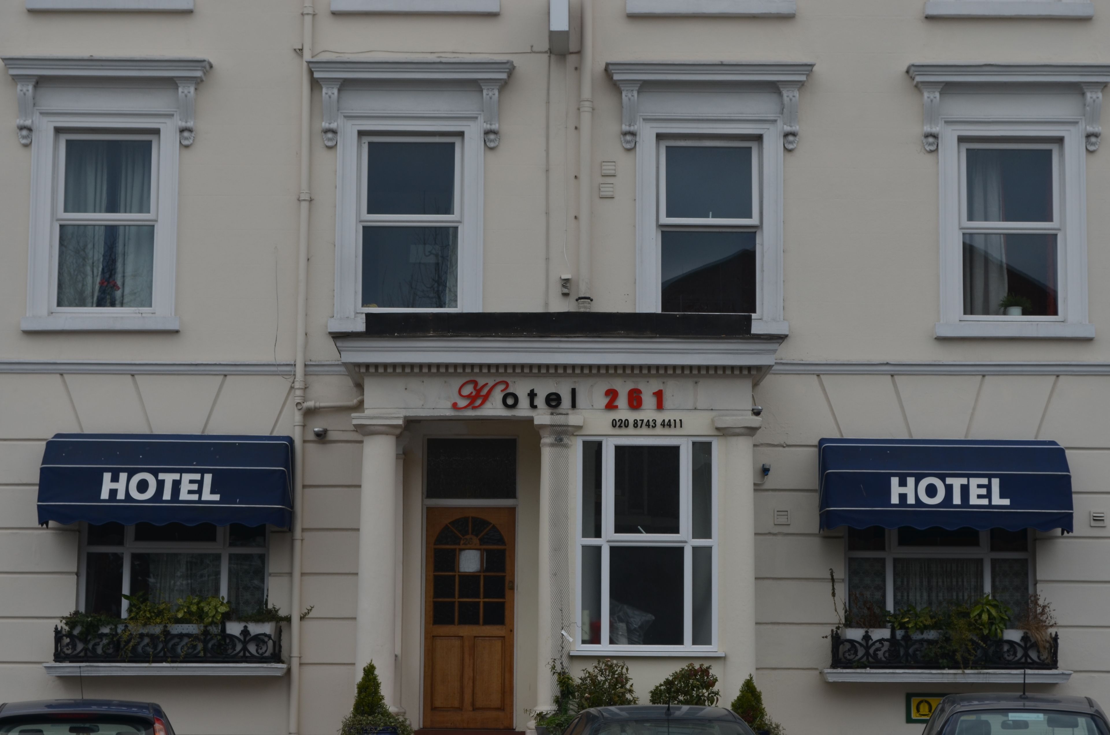 En hotellfasad med en central entré, två sidoflyglar och en skylt med texten ”Hotell 261”.
