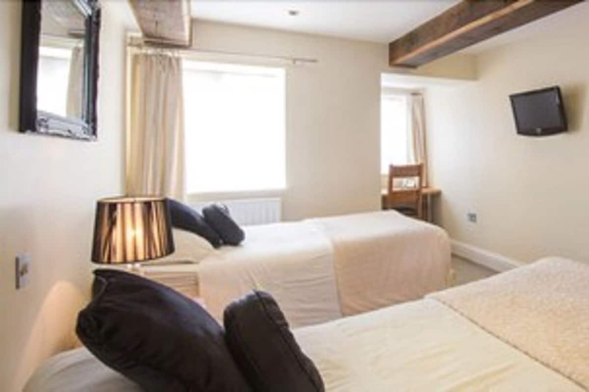 A hotel room with two beds, a TV mounted on the wall, and a wooden door.