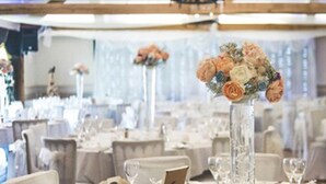 A banquet hall with round tables set for a formal event, featuring floral centerpieces and white tablecloths. - The Newtown House Hotel (Hayling Island)